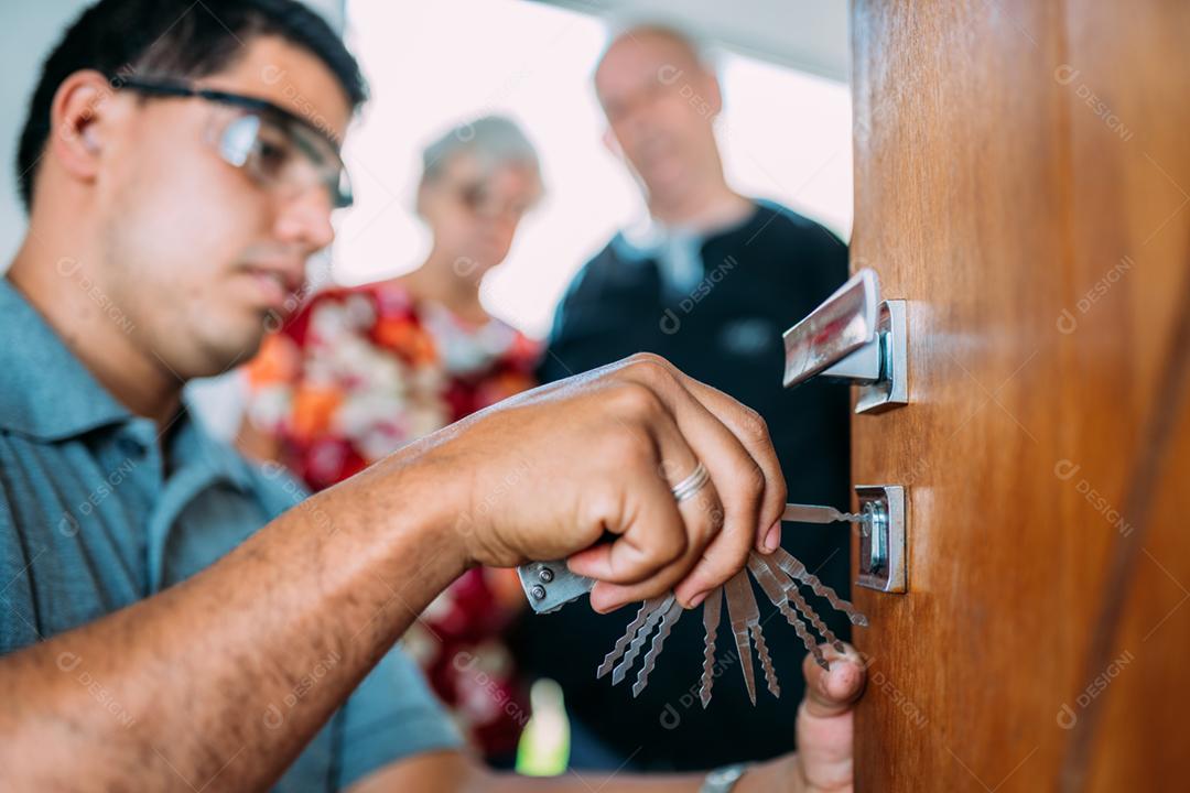 Close-up de mãos masculinas reparando ou instalando uma fechadura de porta de metal