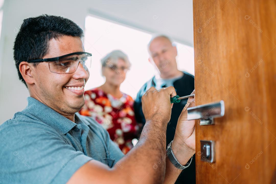 Close-up de mãos masculinas reparando ou instalando uma fechadura de porta de metal