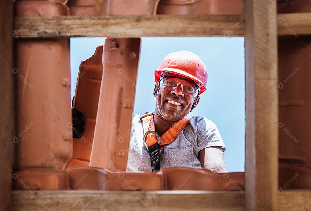 Trabalhador latino instalando telhas de cerâmica amarela montadas
