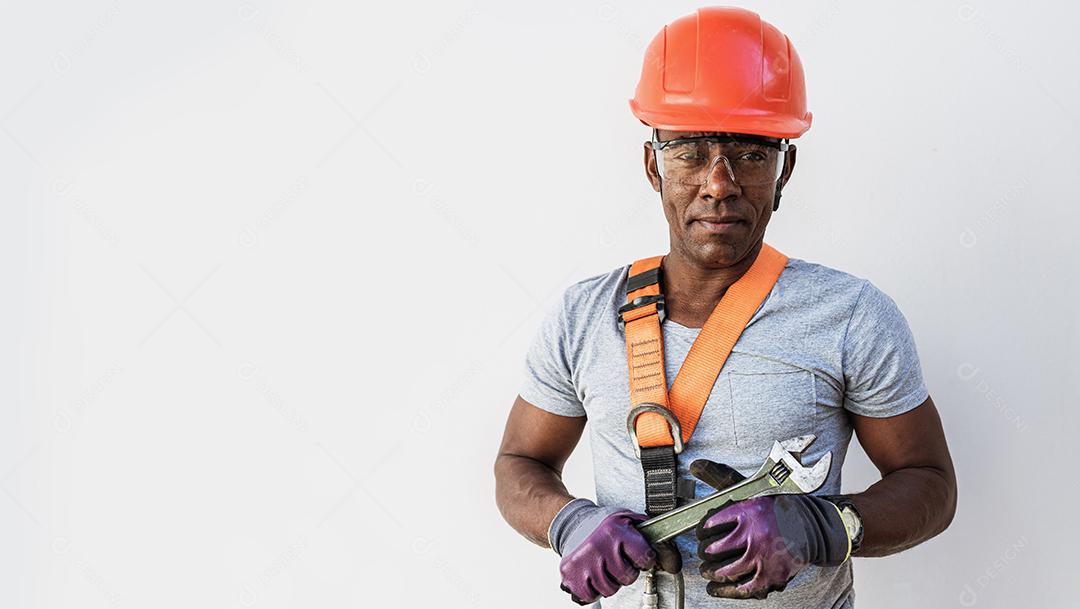 Trabalhador latino instalando telhas de cerâmica amarela montadas em tábuas de madeira cobrindo telhado residencial em construção.