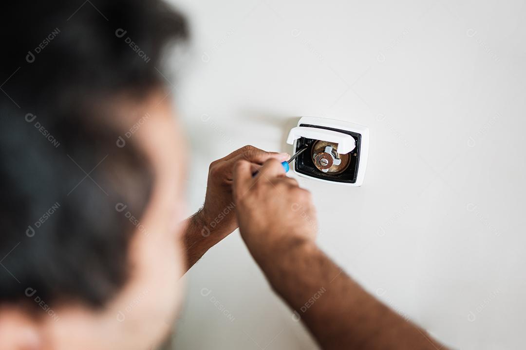 Encanador consertando botão de descarga no banheiro da casa.