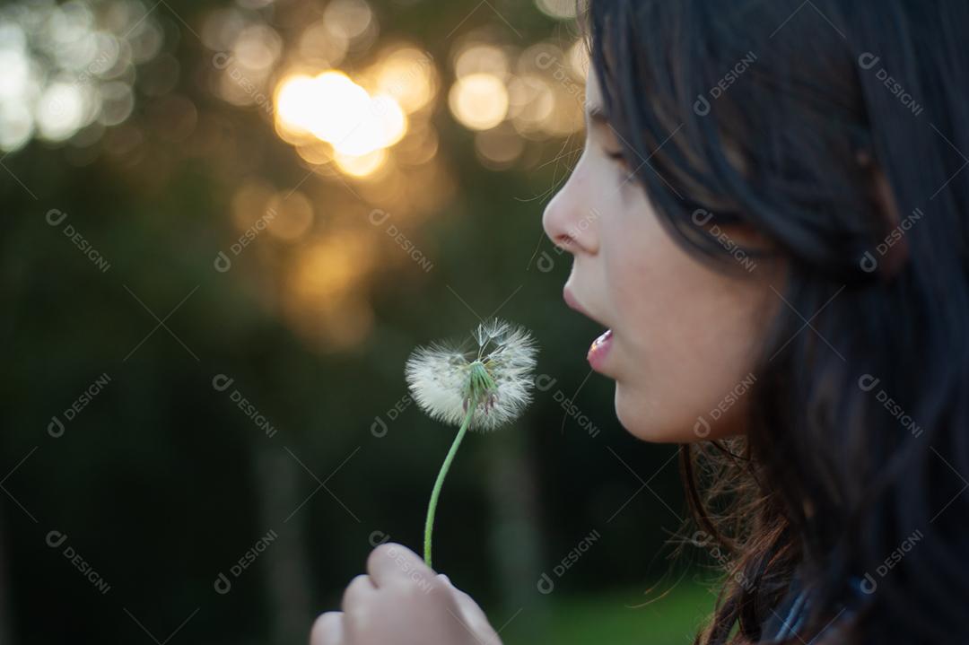 Garota criança soprando um dente de leão planta flor