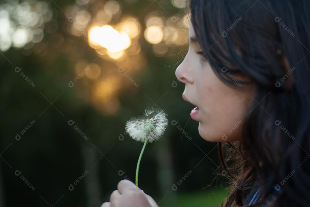 Garota criança soprando um dente de leão planta flor