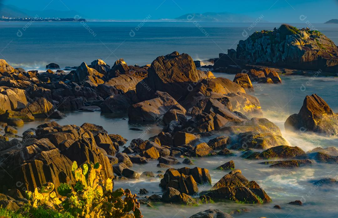 Paisagem por do sol praia pedreiras pedras rochas lago céu nublado