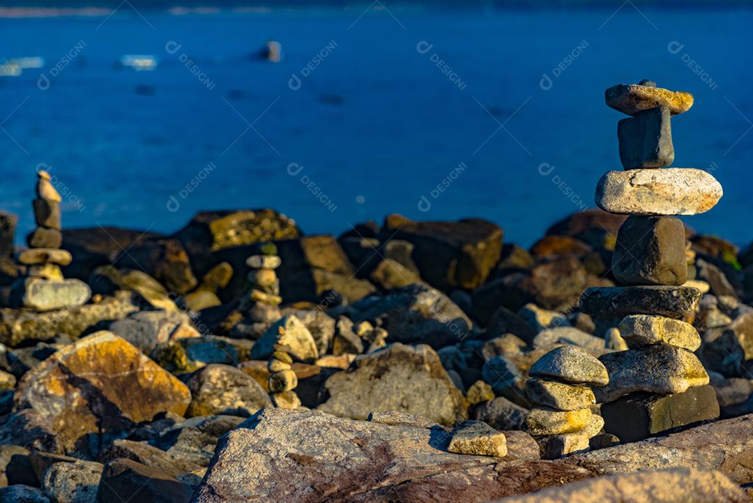 Paisagem por do sol praia pedreiras pedras rochas lago céu nublado
