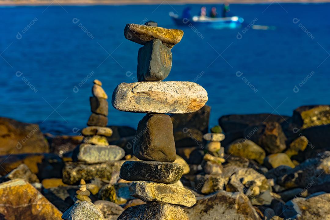 Paisagem por do sol praia pedreiras pedras rochas lago céu nublado