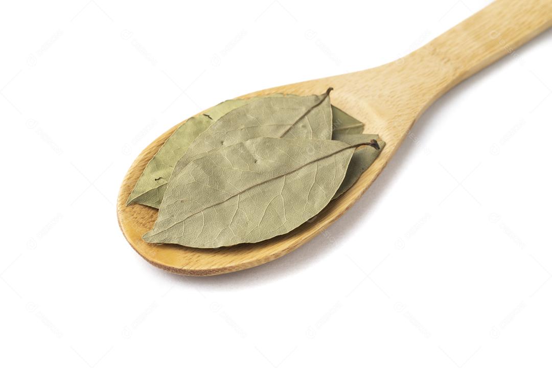 Vista superior, closeup de folhas de louro secas em uma colher de pau.