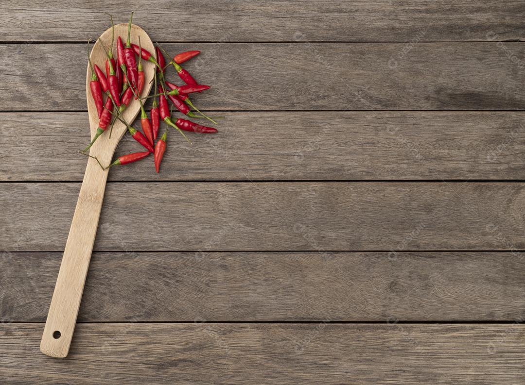 Pimenta malagueta vermelha em uma colher sobre a mesa de madeira