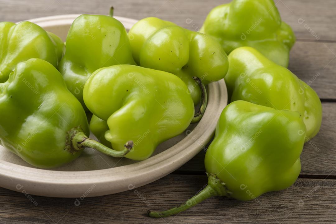 Pimenta cambuci verde, ingrediente da culinária brasileira, em um prato sobre a mesa de madeira.