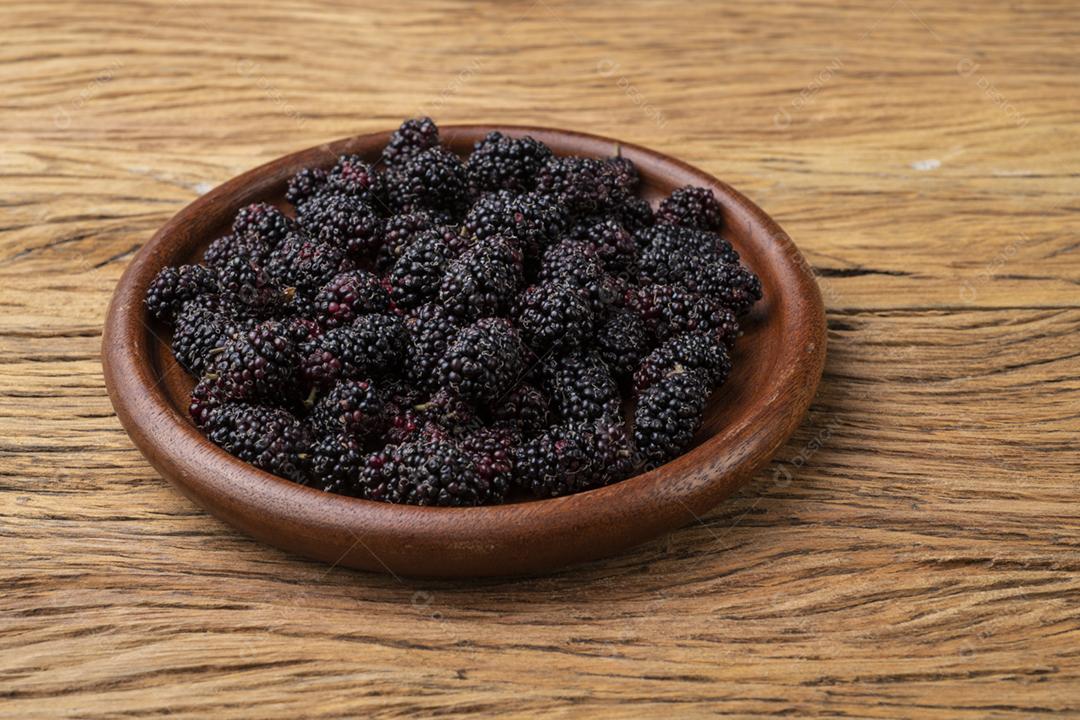 Amoras em um prato sobre a mesa de madeira.