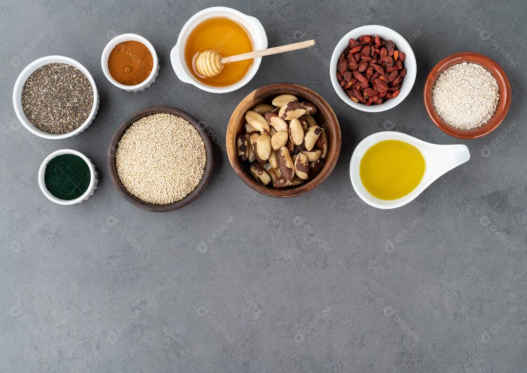 Superalimentos variados sobre fundo de pedra Chia, quinoa, aveia, linhaça, mel, espirulina e outros.