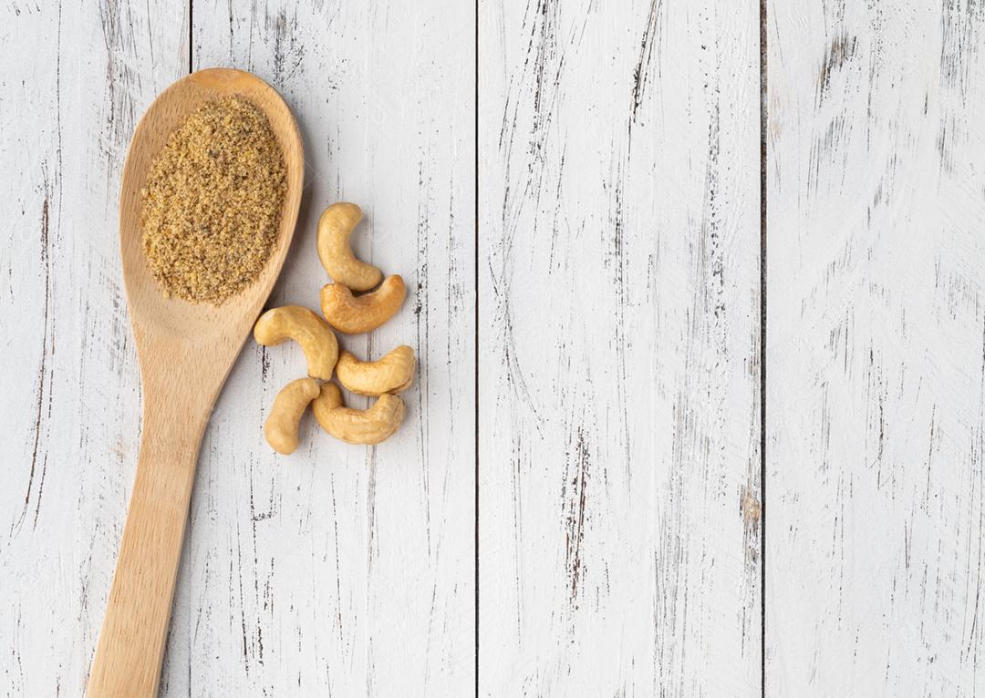 Farinha de castanha de caju em uma colher sobre a mesa de madeira com espaço de cópia. Farinha sem glúten.