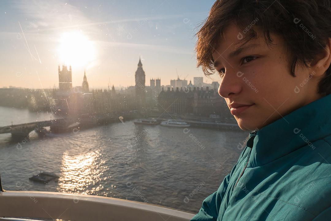 Menino dentro da London Eye com a cidade de Londres ao fundo