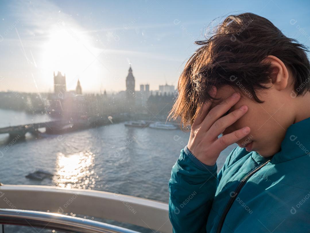 Menino dentro da London Eye com a cidade de Londres ao fundo