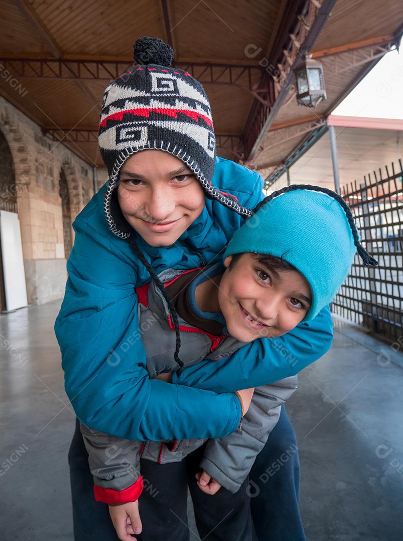 Irmãos posando para a câmera na estação de trem no inverno