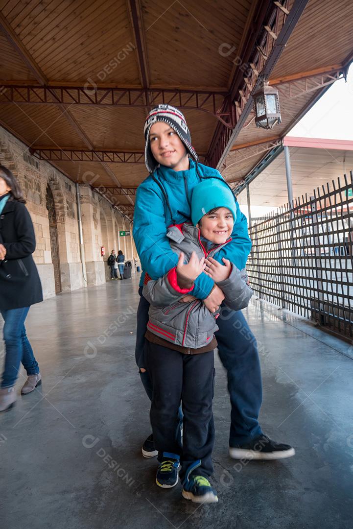 Irmãos posando para a câmera na estação de trem no inverno