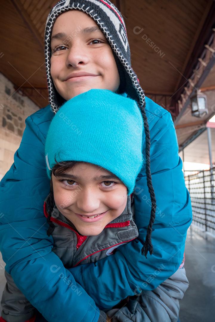Irmãos posando para a câmera na estação de trem no tempo de inverno