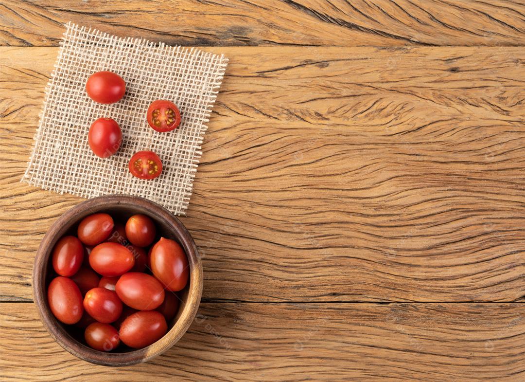 Tomate cereja em uma tigela sobre a mesa de madeira