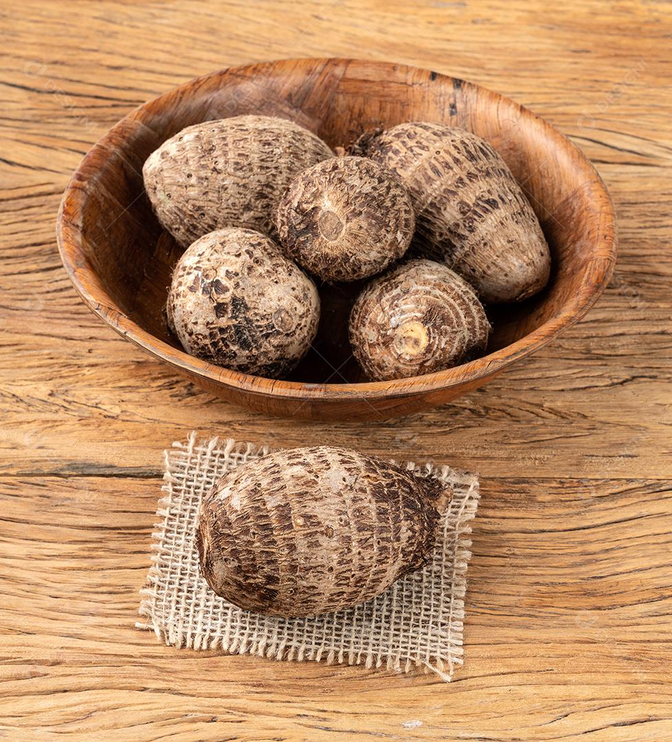 Inhames crus ou inhames em uma tigela sobre mesa de madeira