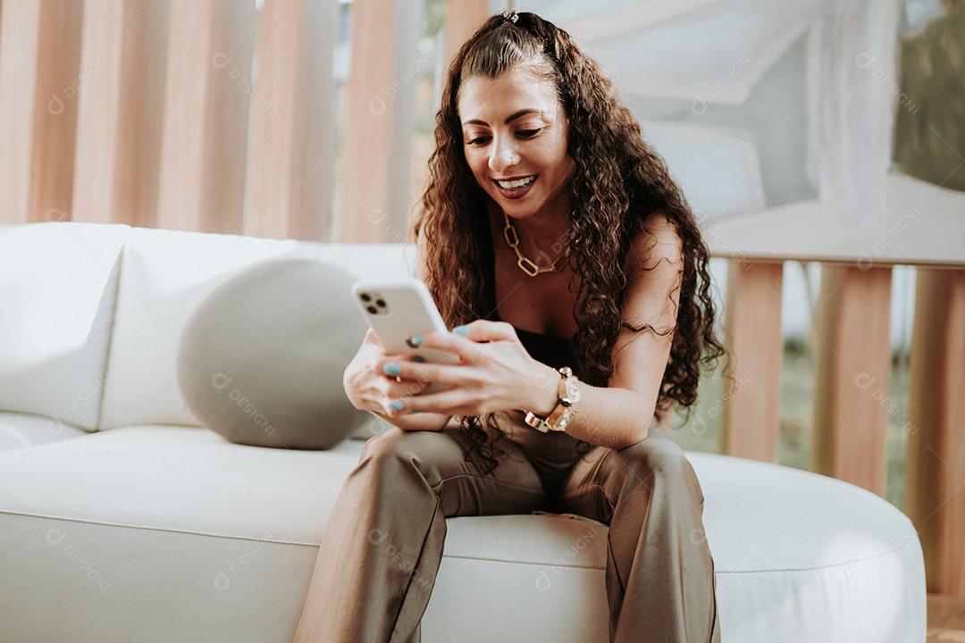 Uma jovem linda mulher latina na mesa segurando smartphone