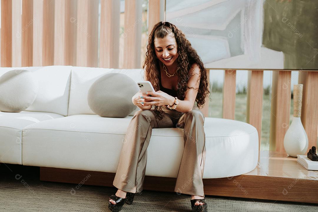 Uma jovem linda mulher latina na mesa segurando smartphone