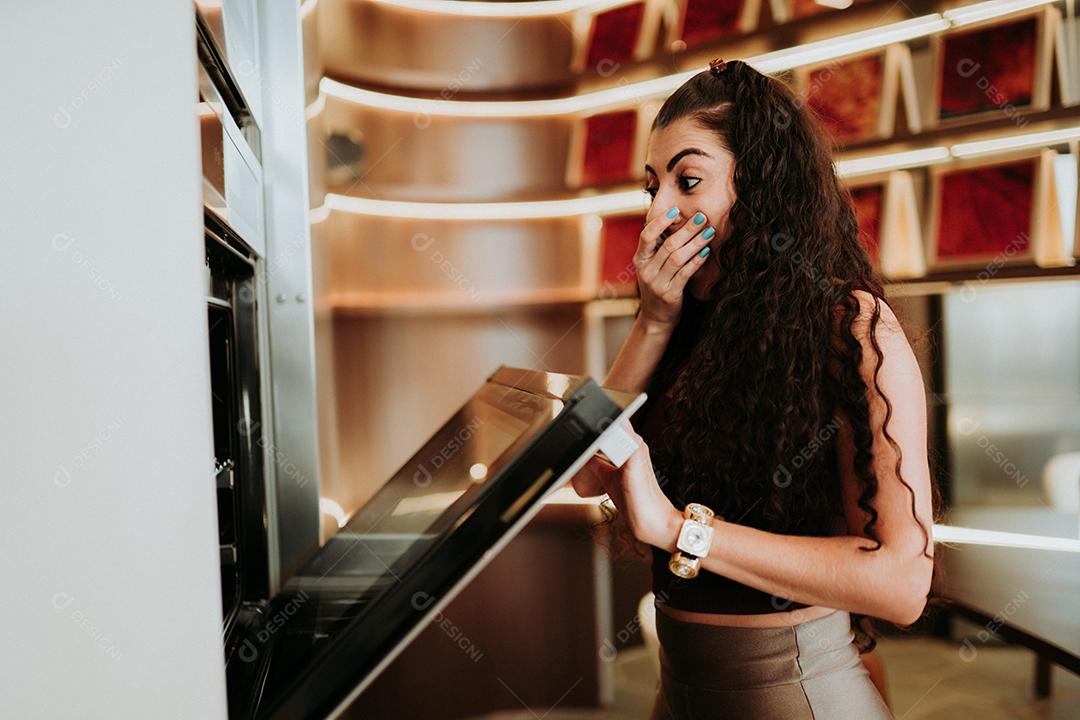 Mulher latina de pé ao lado do forno e verificando sua receita