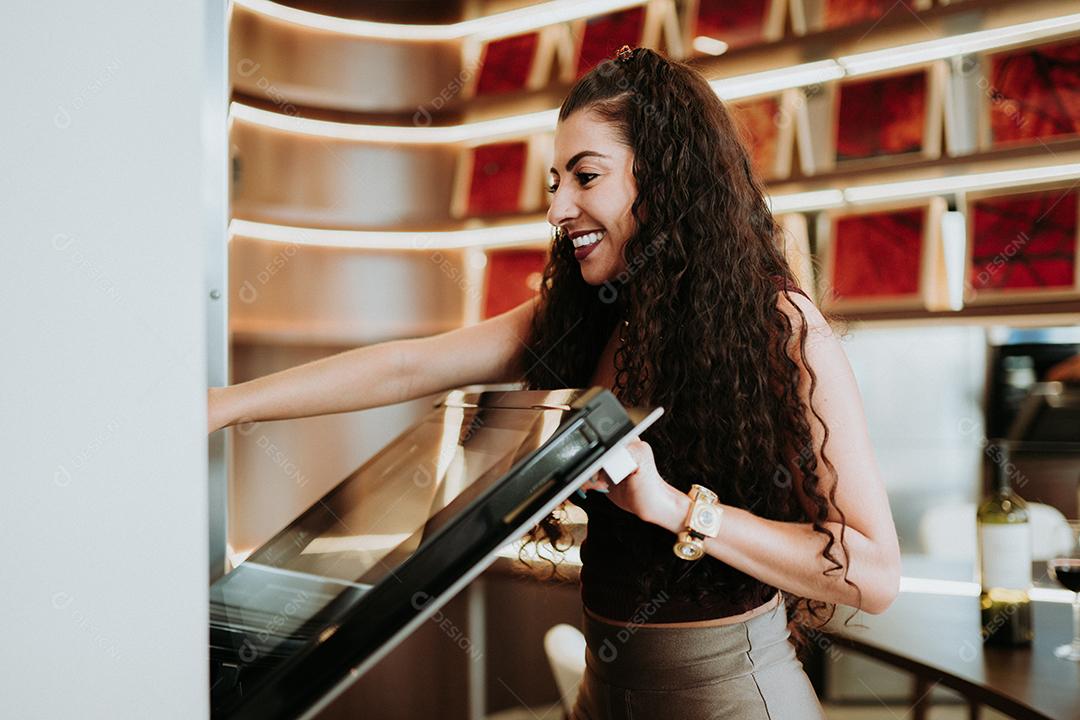 Mulher latina de pé ao lado do forno e verificando sua receita