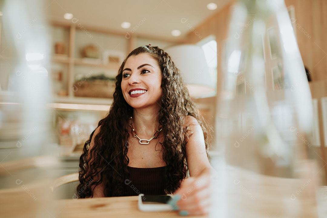 Feliz dama latina relaxa em casa sozinha, compartilha boas notícias nas mídias sociais via celular