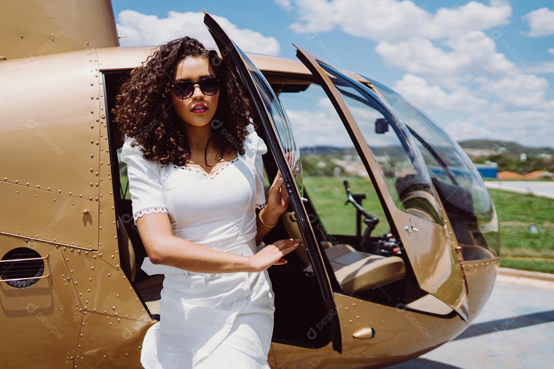 Mulher bem sucedida sendo fotografada perto de um Helicóptero