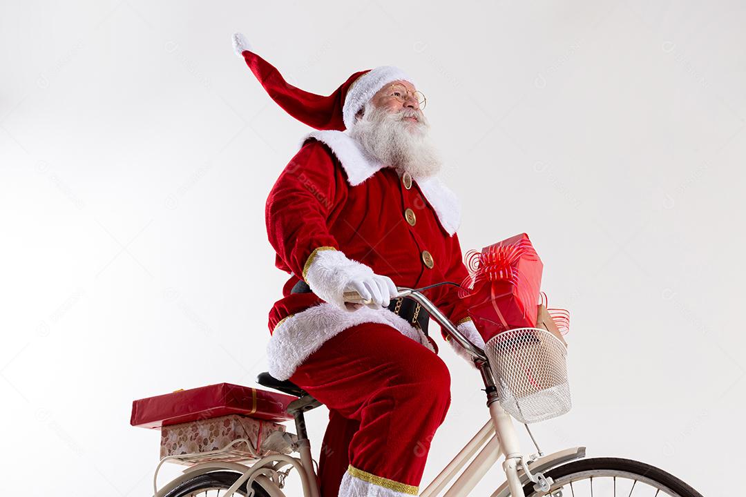 Papai Noel de bicicleta entregando presentes de Natal.