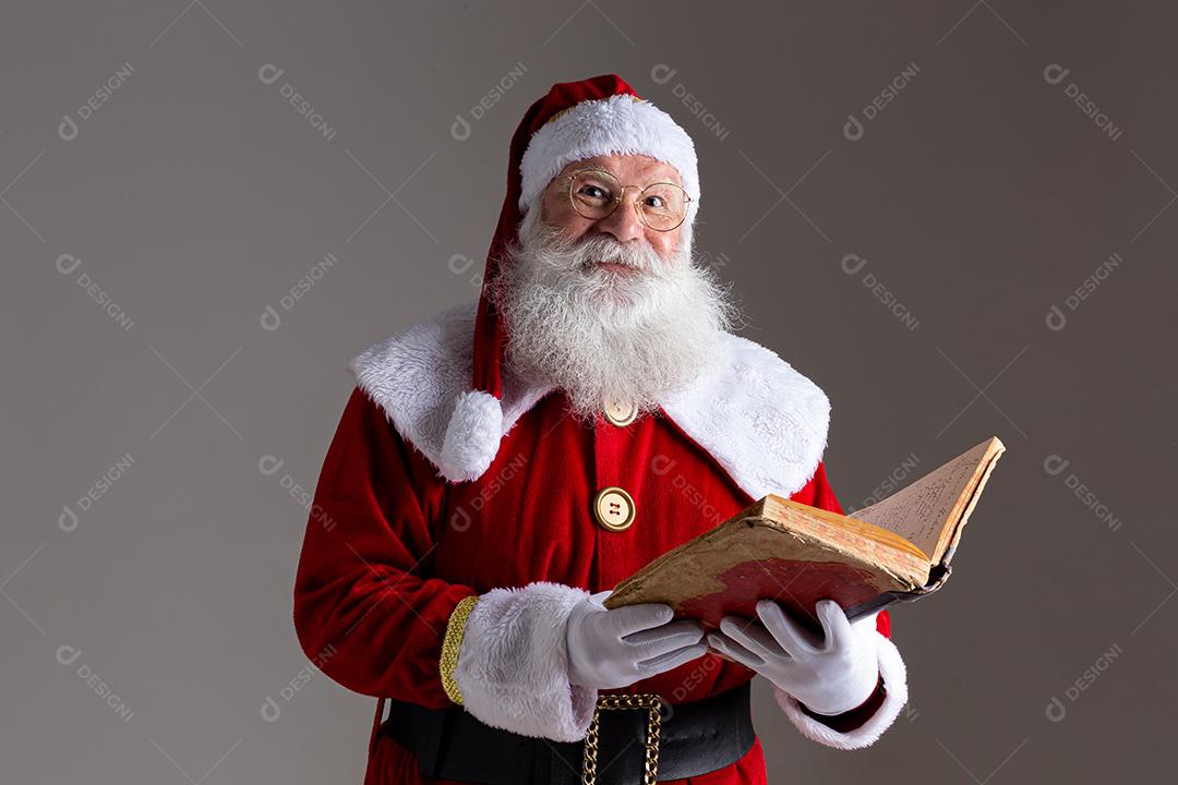 Papai Noel com um velho livro de capa vermelha. Anotando presentes de nomes