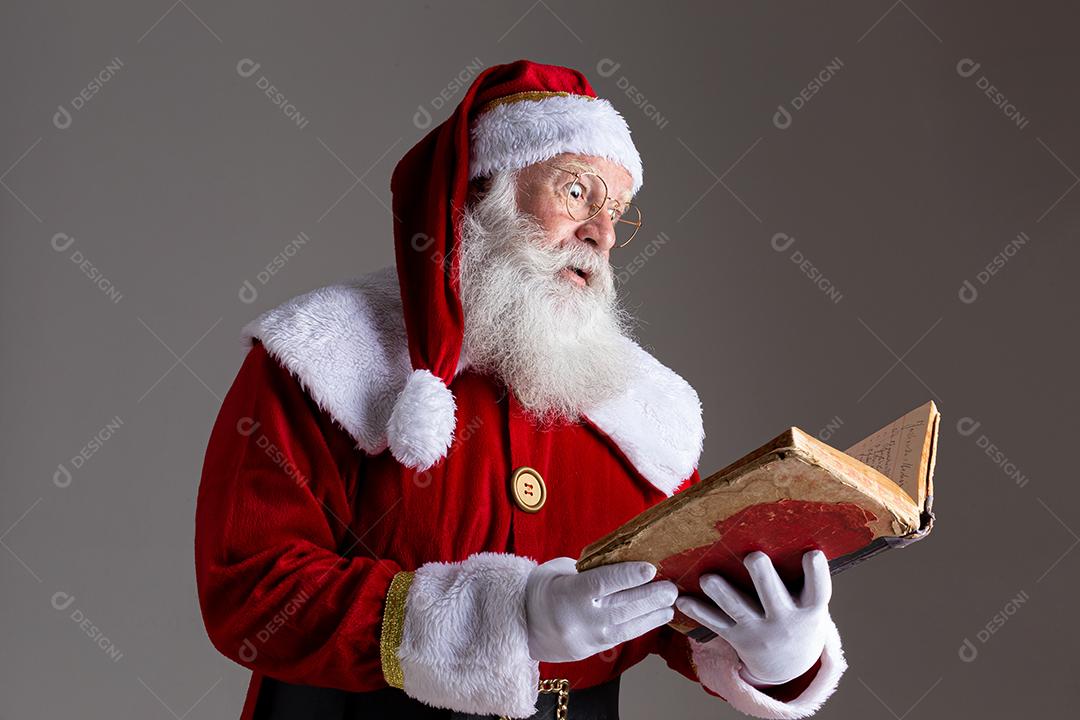 Papai Noel com um velho livro de capa vermelha. Anotando presentes de nomes