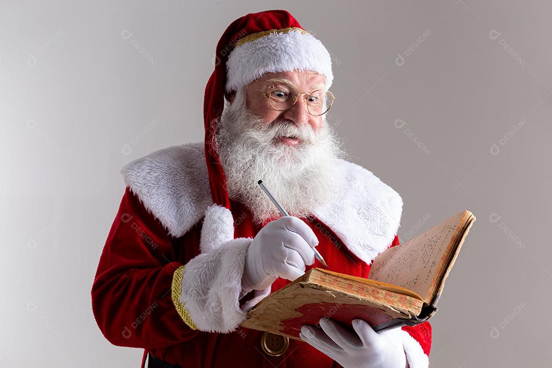 Papai Noel com um velho livro de capa vermelha. Anotando presentes de nomes