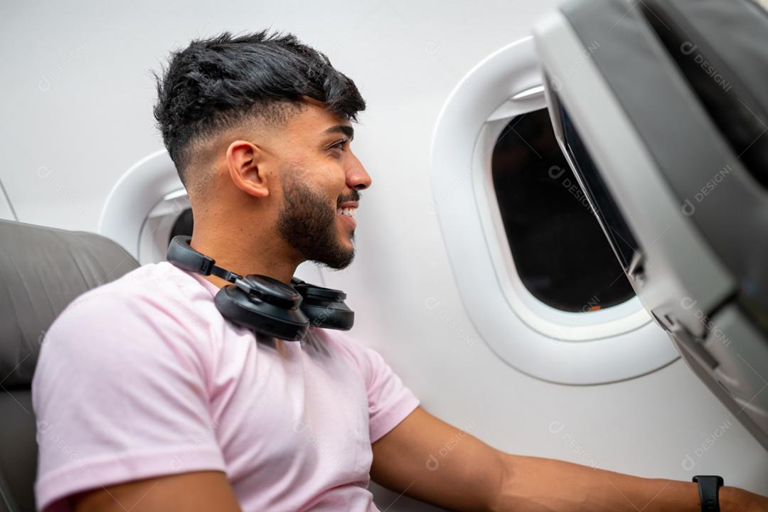 jovem latino-americano usando máscara facial protetora, viajando de avião. Nova viagem normal após o conceito