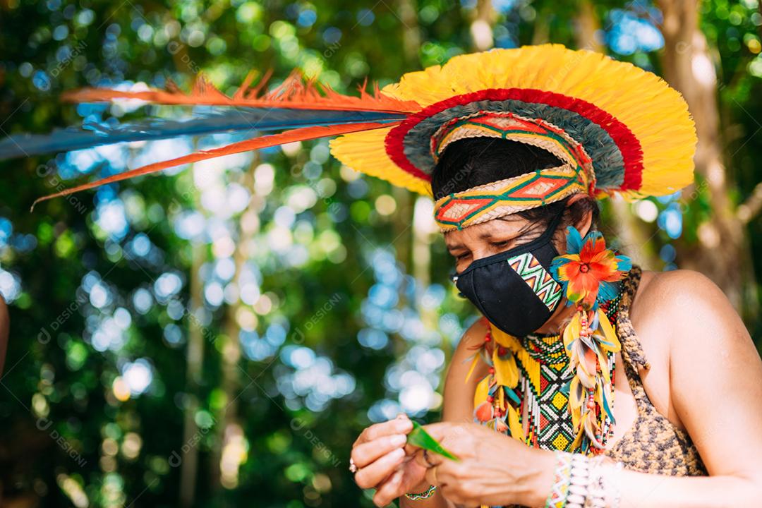 Índio da tribo Pataxó com cocar de penas e máscara de proteção contra a pandemia de covid-19