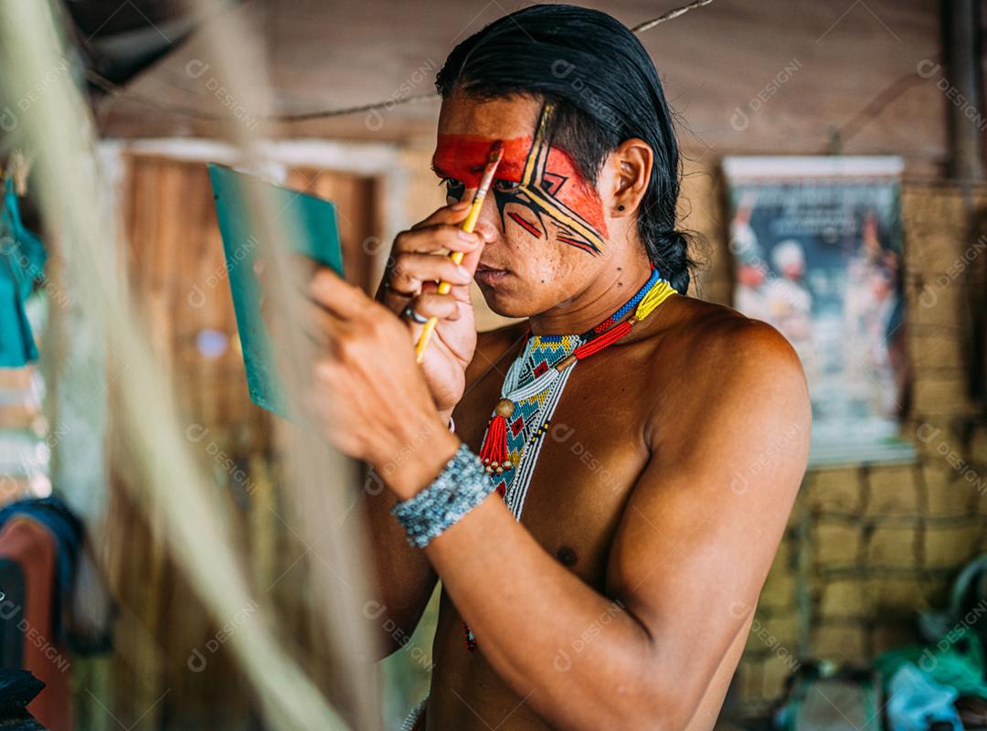 Índio da tribo Pataxó, usando espelho e pintando o rosto.