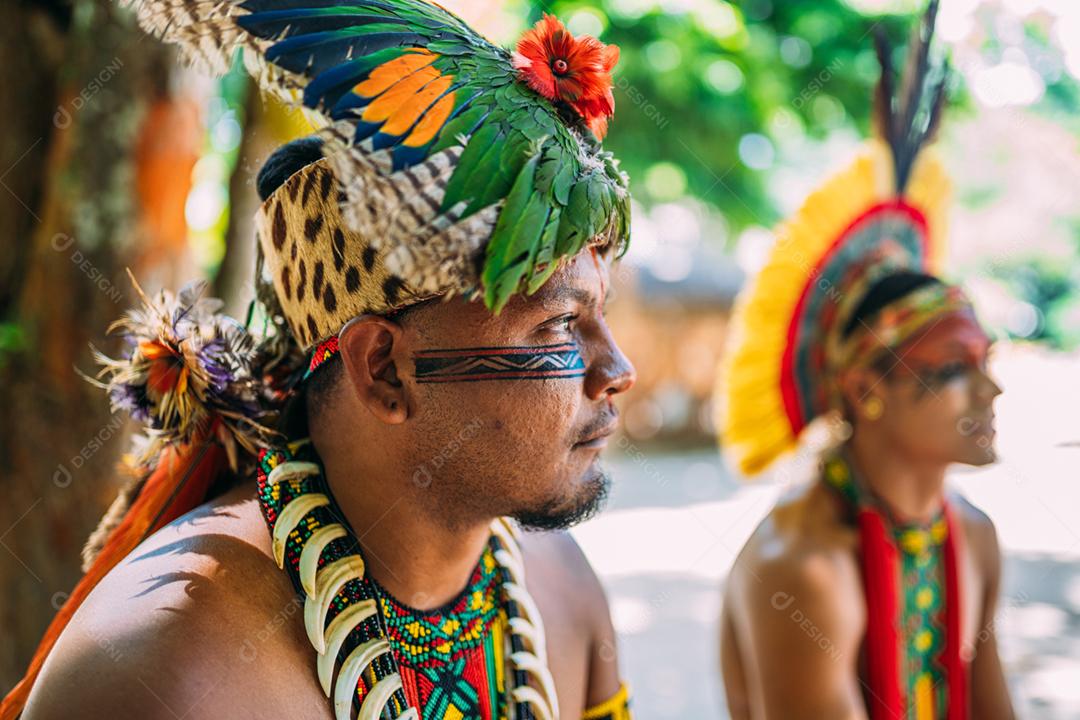 Chefe da tribo Pataxó. Índio brasileiro com cocar de penas, colar e pinturas faciais tradicionais olhando para a direita