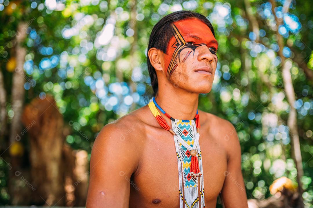 Índio da tribo Pataxó sorrindo. Índio brasileiro do sul da Bahia com colar e pinturas faciais tradicionais olhando para a direita