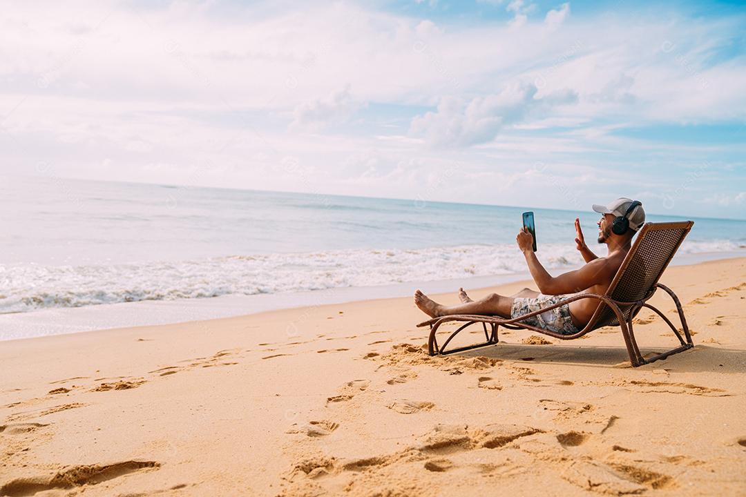 Homem fazendo uma chamada de vídeo nas férias de verão. homem latino-americano