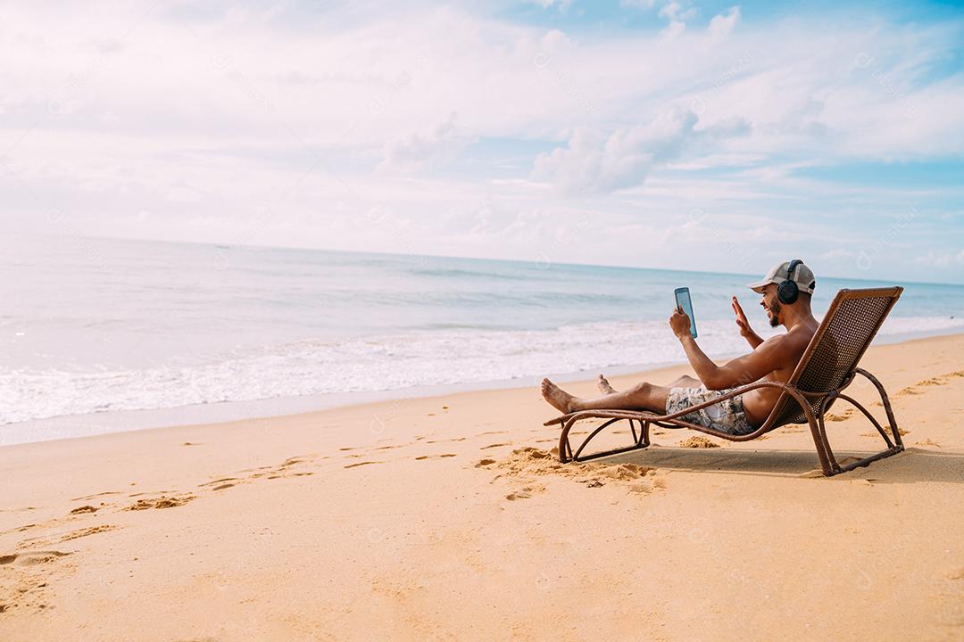 Homem fazendo uma chamada de vídeo nas férias de verão. homem latino-americano