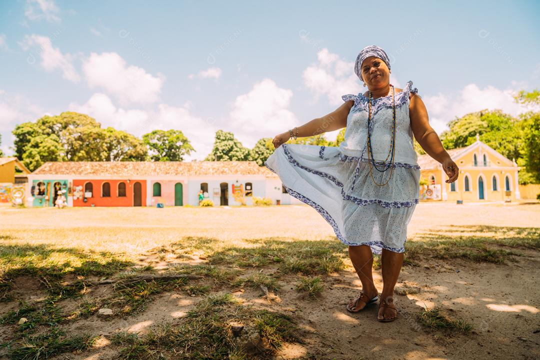 Feliz mulher brasileira vestida com o tradicional traje baiano da religião Umbanda, no centro histórico de Porto Seguro