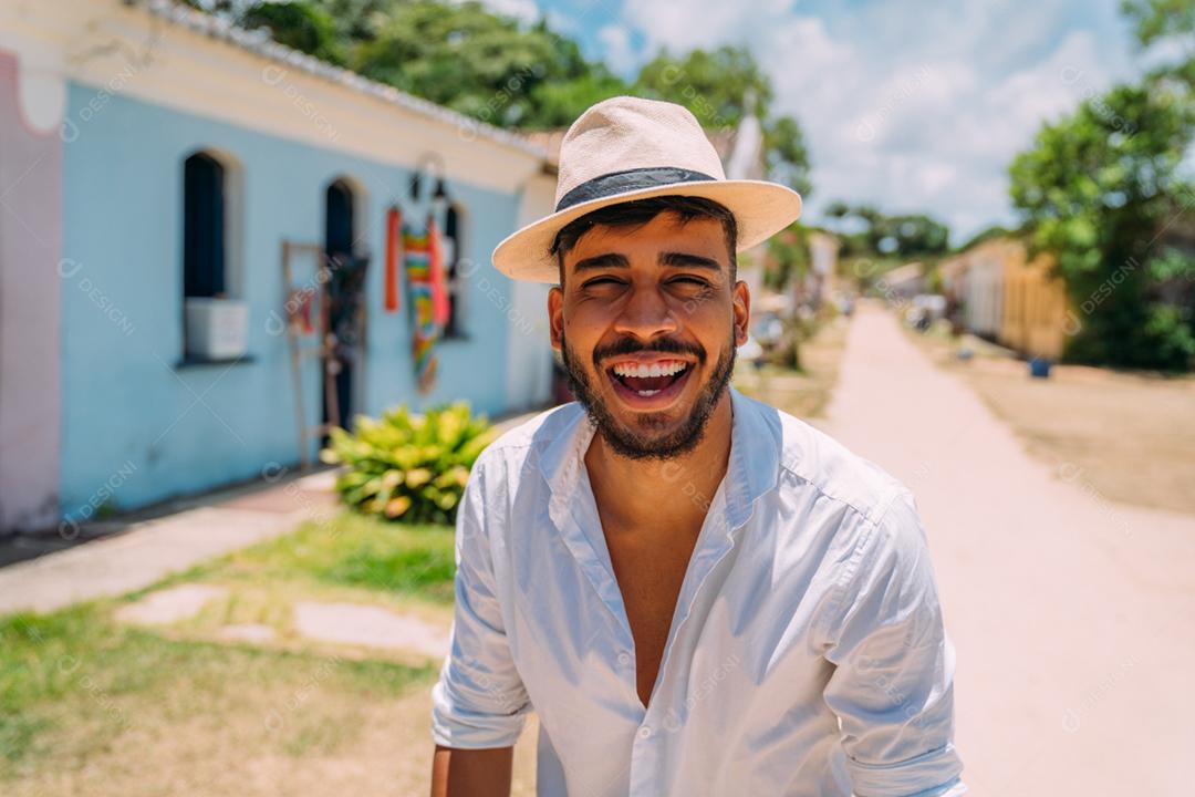Turista fazendo selfie no centro histórico de Porto Seguro. Homem latino-americano de chapéu sorrindo para a câmera