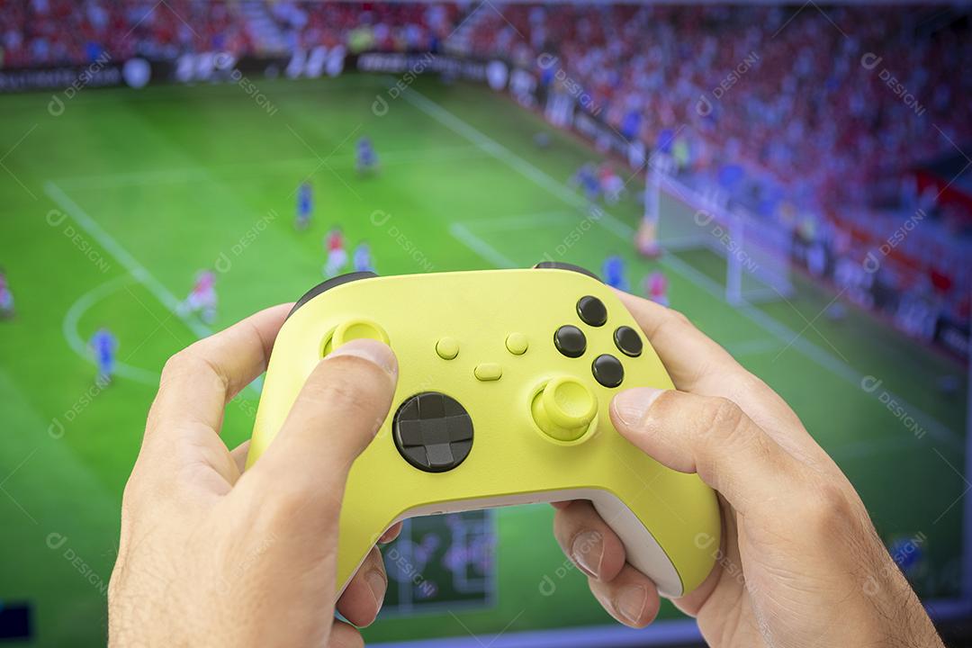 Homem segurando controlador de jogo jogando futebol.