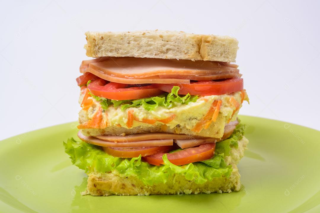 Sanduíche grande com presunto defumado, com alface e tomate na chapa verde. Comida rápida.