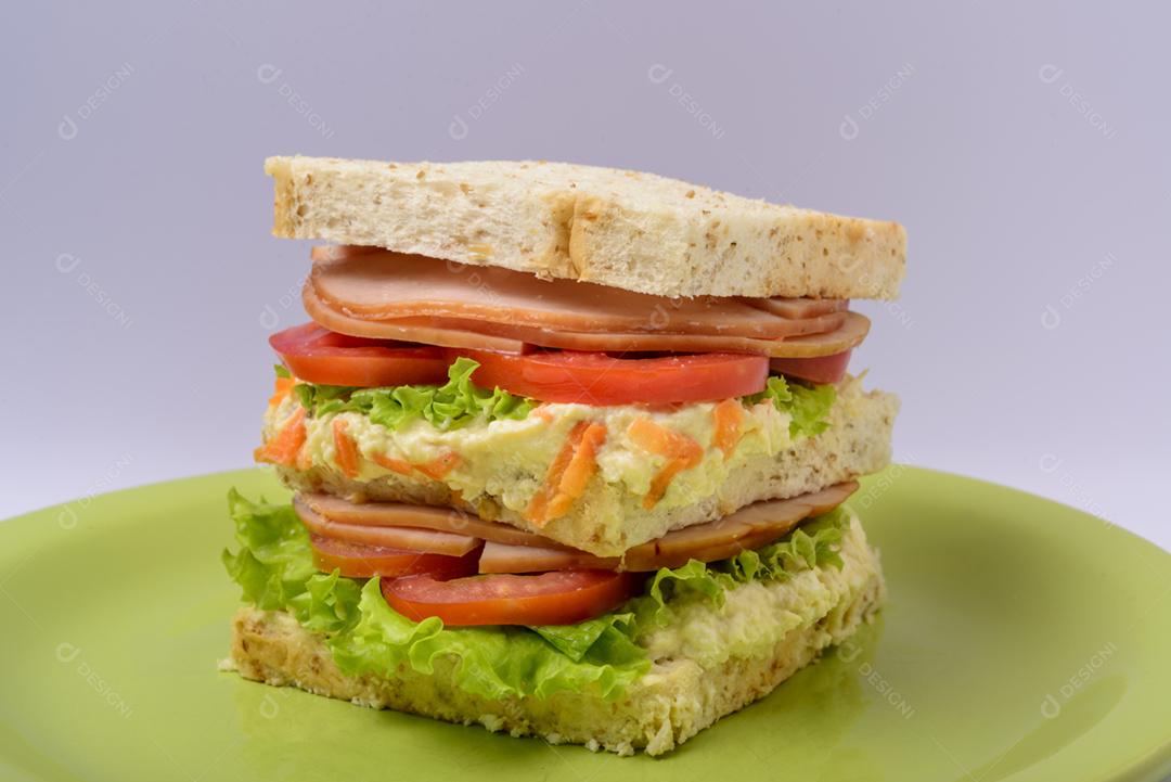 Sanduíche grande com presunto defumado, com alface e tomate na chapa verde. Comida rápida.