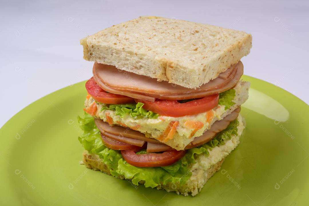 Sanduíche grande com presunto defumado, com alface e tomate na chapa verde. Comida rápida.