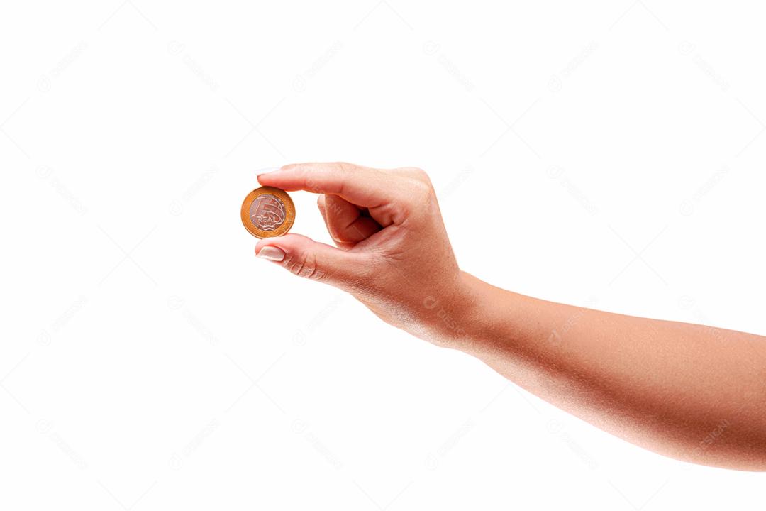 Mão segurando uma moeda real do Brasil em fundo amarelo. Conceito de finanças.