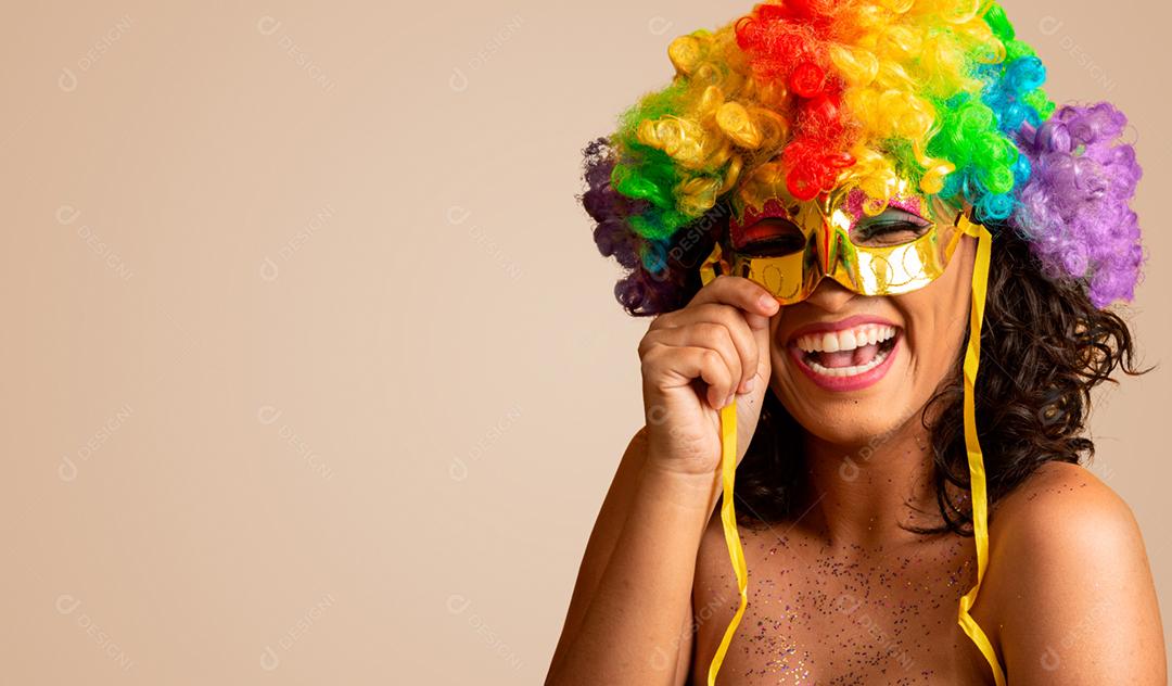 Mulher bonita vestida para a noite de carnaval. Mulher sorridente pronta para curtir o carnaval com uma peruca colorida e máscara