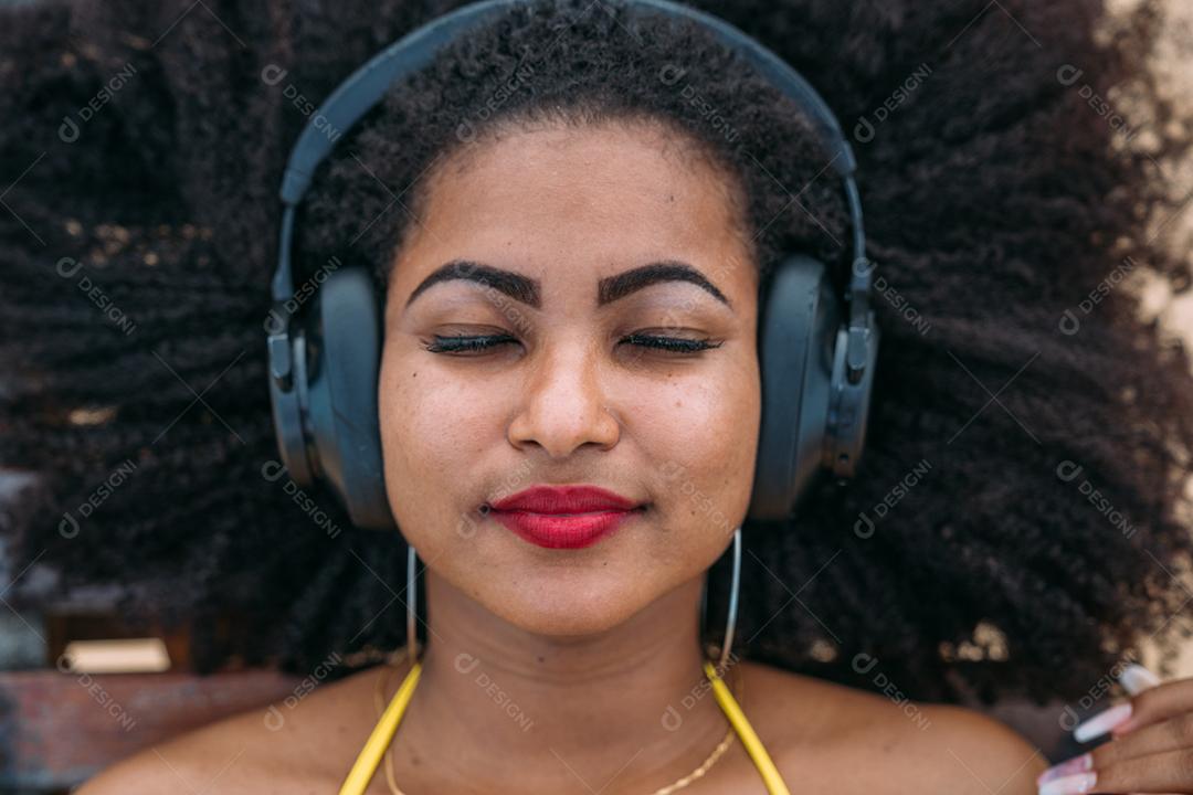 férias de verão, tecnologia e conceito de internet. mulher latino-americana ouvindo música com fone de ouvido