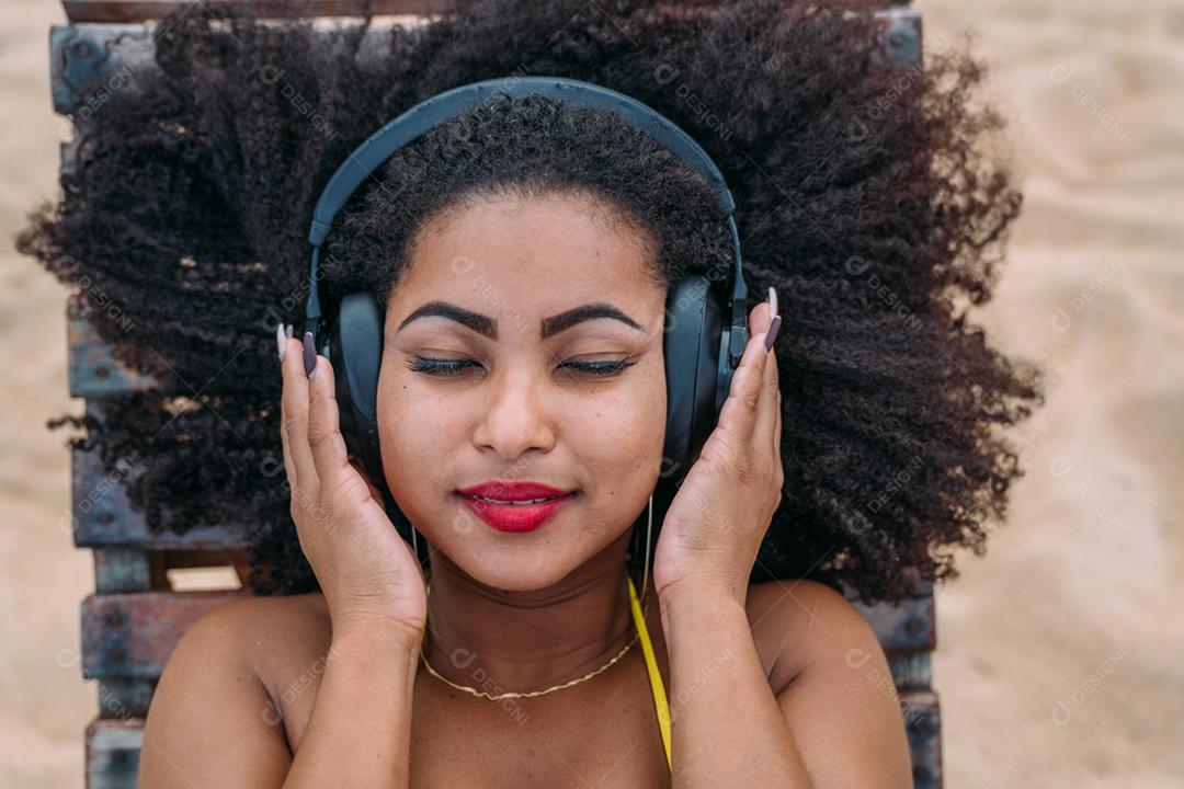 férias de verão, tecnologia e conceito de internet. mulher latino-americana ouvindo música com fone de ouvido